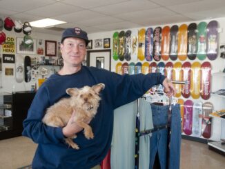 Lucas Underwood holding the small dog, Ozzi, next to skateboard parts.
