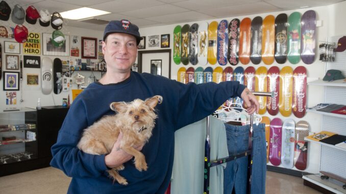 Lucas Underwood holding the small dog, Ozzi, next to skateboard parts.