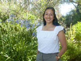 Hatzune Aguilar stands in front of a green background
