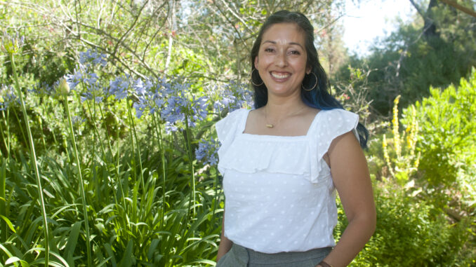 Hatzune Aguilar stands in front of a green background