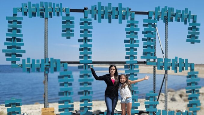 A woman and girl stand in front of body of water