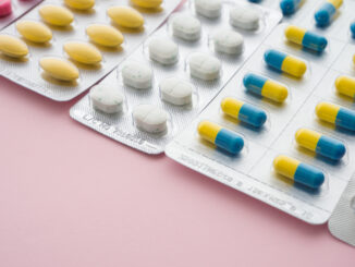 Various kinds of medications in blister packs on a pink background