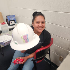 Photo of Nidia Chicas in an office holding a hard hat