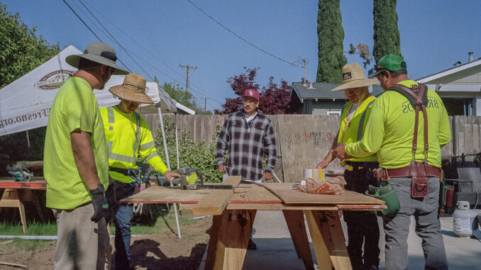 Jose Nunez doing construction work in a yard with four other men in hi-vis gear