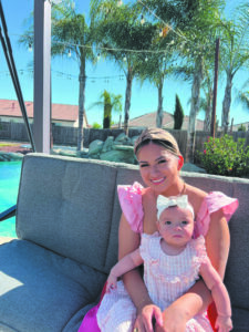 Imelda Ramirez sitting in a yard with palm trees with a baby on her lap