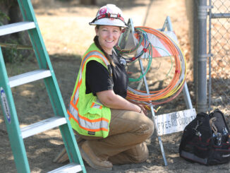 Alexis Rowberry in construction gear kneeling at a construction site outside