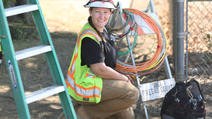 Alexis Rowberry in construction gear kneeling at a construction site outside