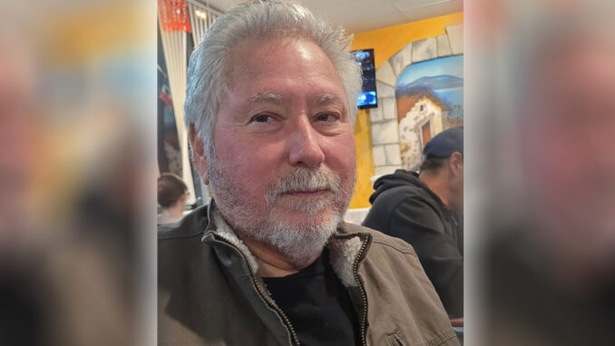 A selfie of Josue Salazar, an older man with gray hair and a gray beard in a brown jacket