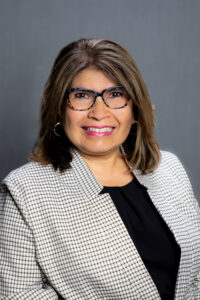 Professional photo of Teresa Smith, a woman with shoulder length brown hair, glasses, and a gray blazer