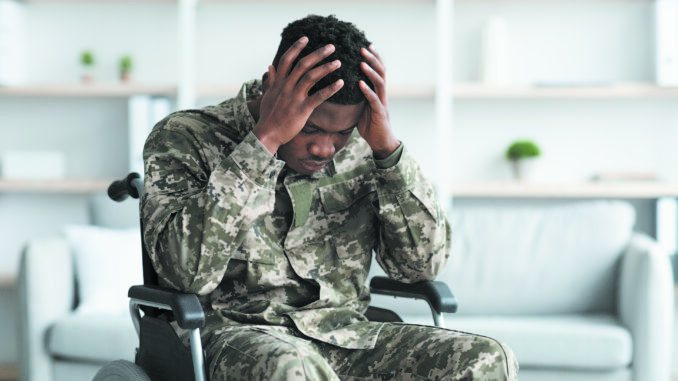 Upset black man sitting in wheelchair, wearing military uniform