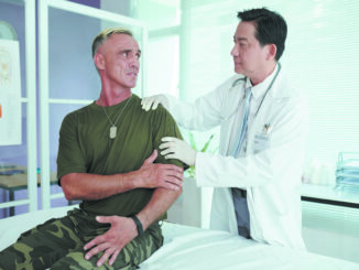 Soldier complaining on his arm while doctor examining it in the ward