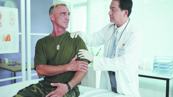 Soldier complaining on his arm while doctor examining it in the ward