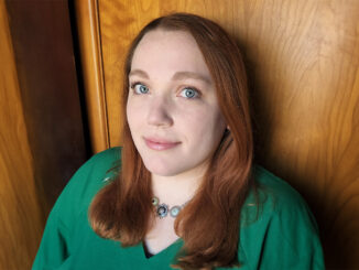 A close portrait of Erin Brunelle, a woman in a green shirt with straight red hair.