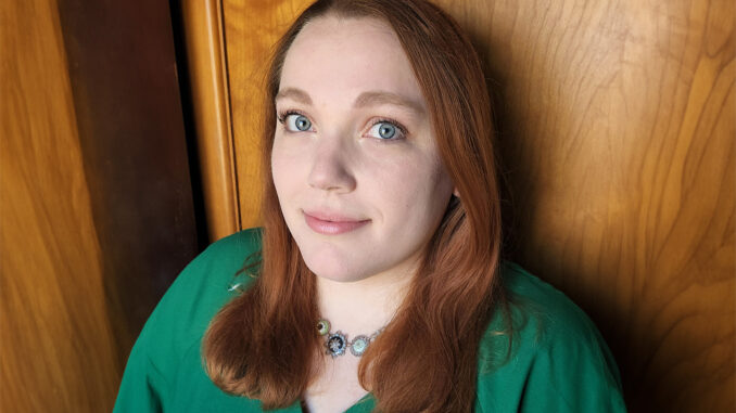 A close portrait of Erin Brunelle, a woman in a green shirt with straight red hair.