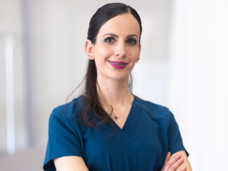 Vanessa Munguia in scrubs standing with her arms crossed and smiling for the camera