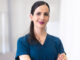 Vanessa Munguia in scrubs standing with her arms crossed and smiling for the camera