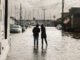 Two silhouetted people standing in a flooded street