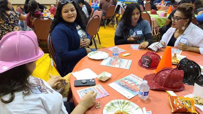 Several Latina women sitting around a table at a community event