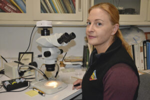 Karen Schultz sitting at a table with a microscope
