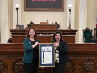 Darcy Totten and Rita Gallardo holding a plaque in the State Assembly
