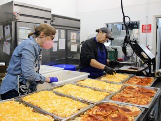 Two women working in a professional kitchen preparing meals.