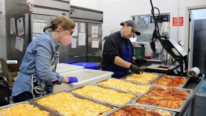 Two women working in a professional kitchen preparing meals.