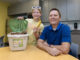 Father and daughter sitting at table with a countertop organic waste pail. The daughter is holding a banana.