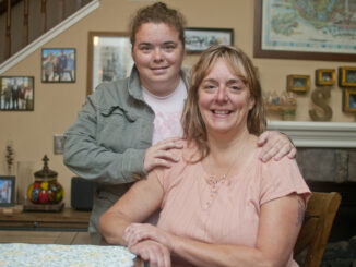 Mother and daughter at the dinner table, embracing and smiling.