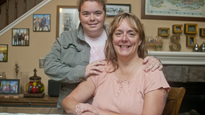 Mother and daughter at the dinner table, embracing and smiling.