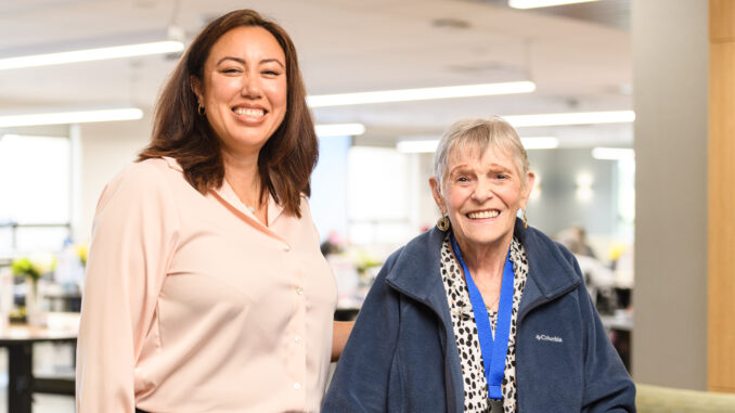 Two women, one older standing next to each other and smiling.