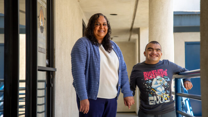 A mother and her son, standing in a hallway, smiling.