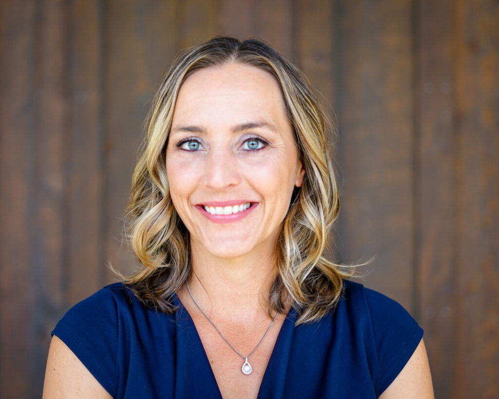 Portrait of a woman smiling with a wood plank background.