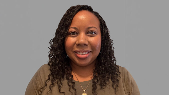 A portrait of a women smiling with a neutral grey background.
